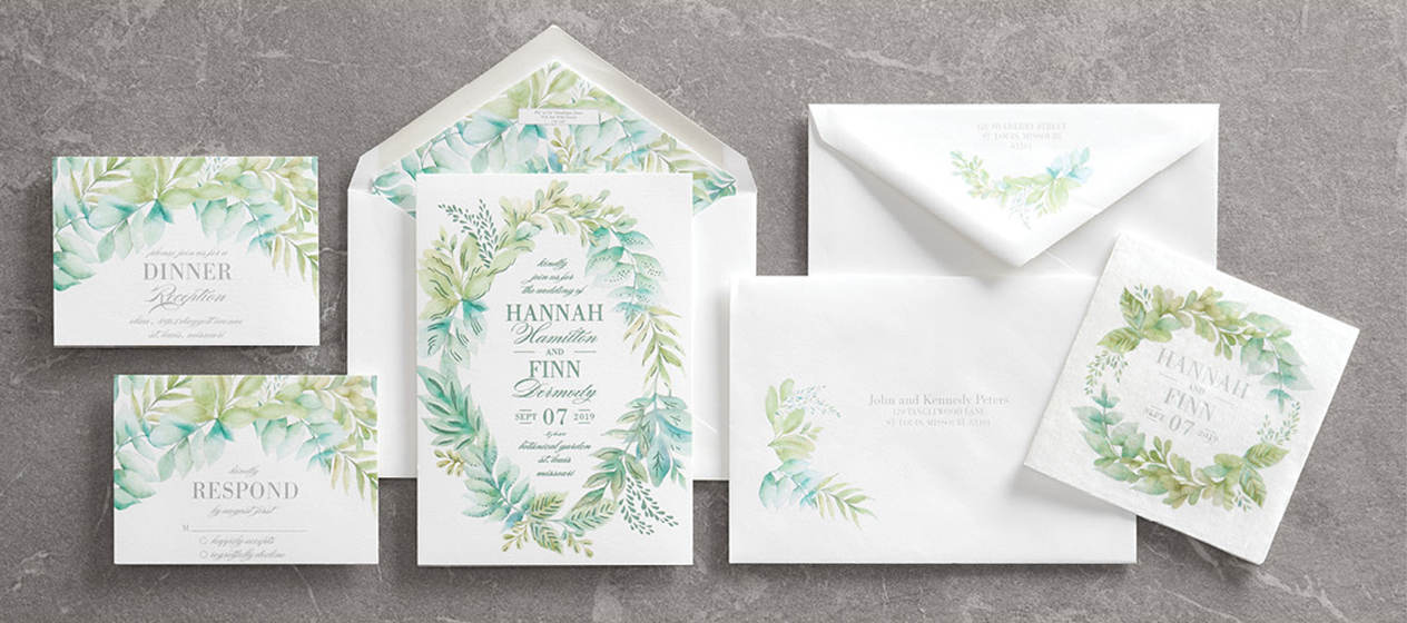 A custom wedding invitation ensemble featuring an elegant greenery design with matching napkin