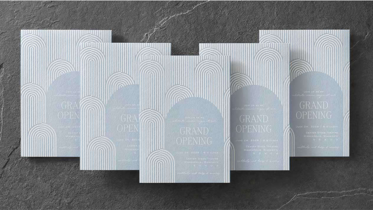 Five custom event invitations with White Ink printing on light blue are stacked in a V formation