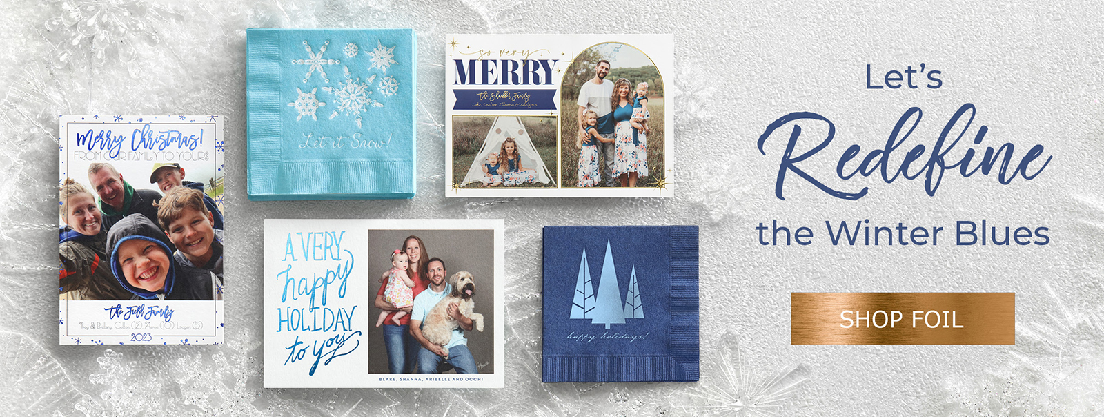 Custom photo holiday cards with different shades of blue foil are laid out on a frosty backdrop.