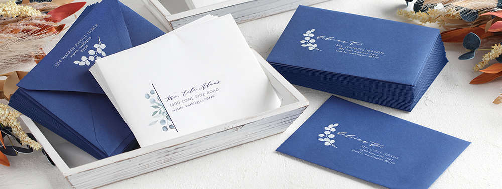 Stacks euro flap envelopes in blue and white featuring variable printing for weddings and events