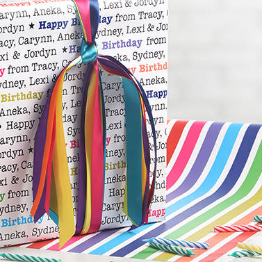 A gift wrapped in personalized wrapping paper with a colorful birthday design and satin ribbons
