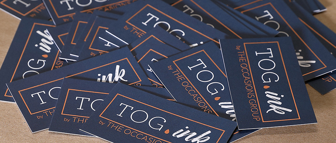 TOG.ink business cards are digitally printed and arranged in a pile on a table.