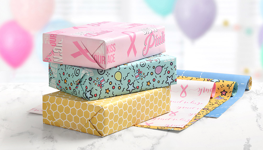 Gifts wrapped in custom wrapping paper are stacked and displayed with colorful balloons in the background. 