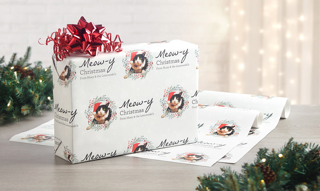 A gift is wrapped in personalized pet wrapping paper featuring a cat in a Santa hat and "Meowy Christams!"