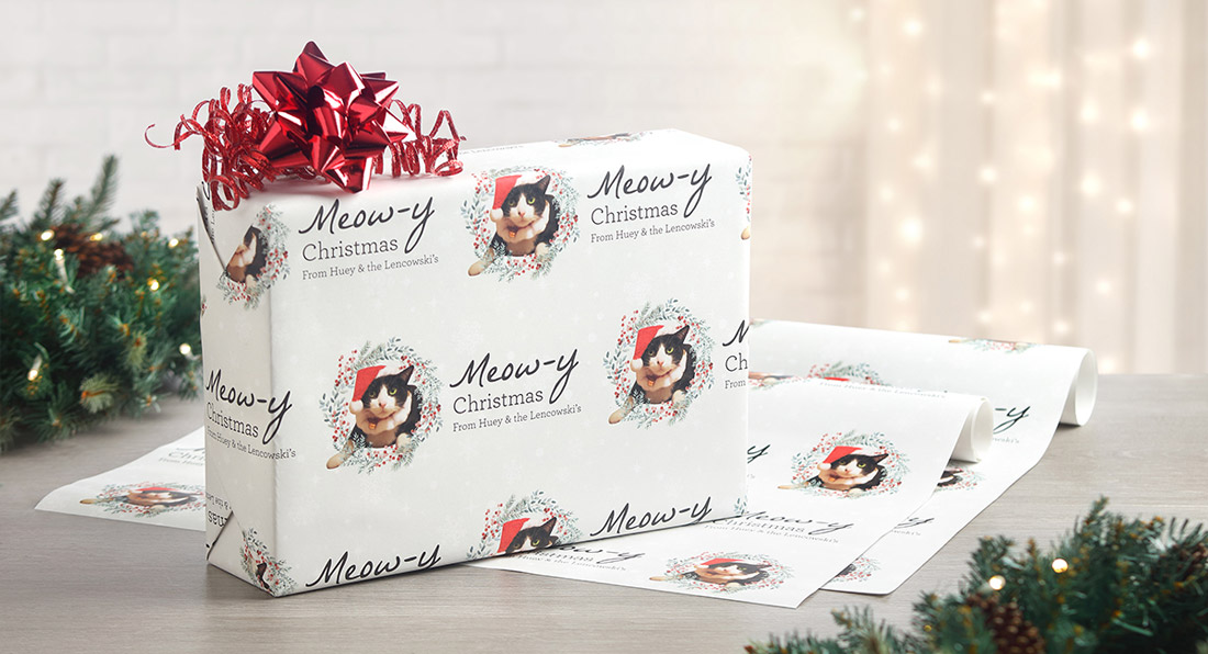 A gift is shown wrapped with personalized pet wrapping paper and a bright red bow on top. 