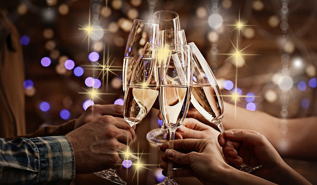 An image of hands holding champagne flutes and toasting to the new year!
