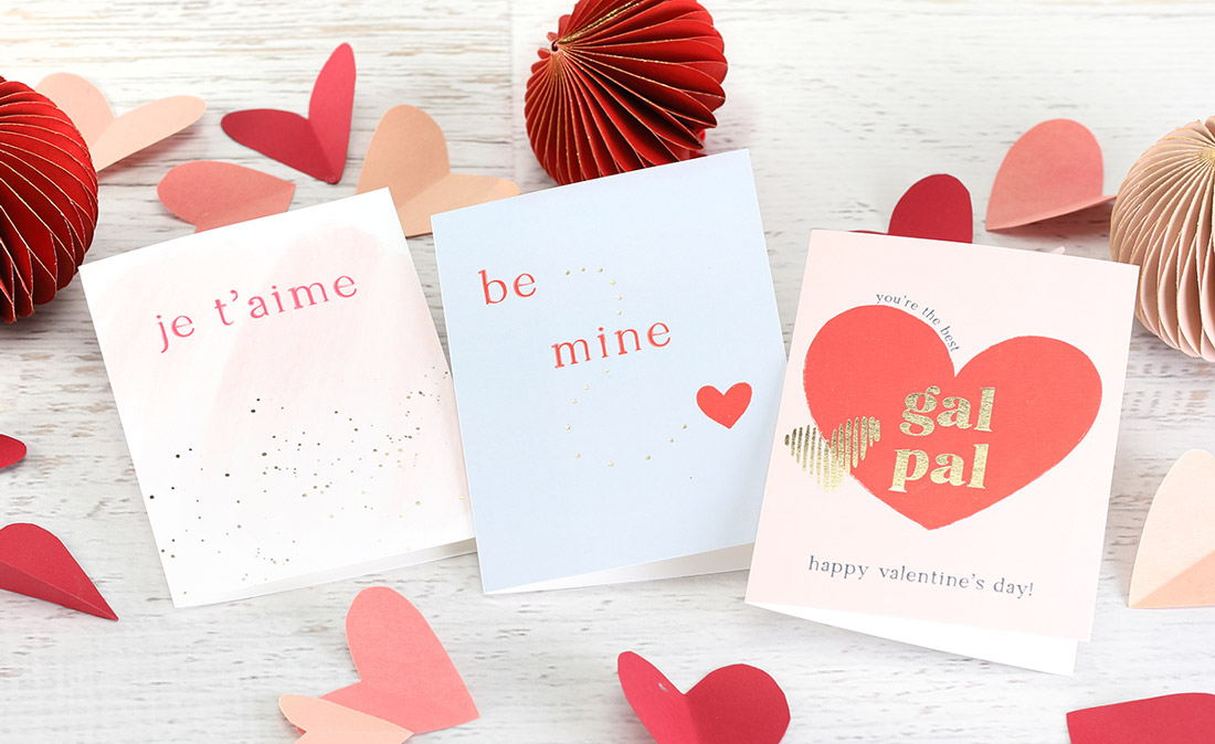 Bright and colorful Valentine's Day cards with gold foil shown with paper hearts and decorations. 