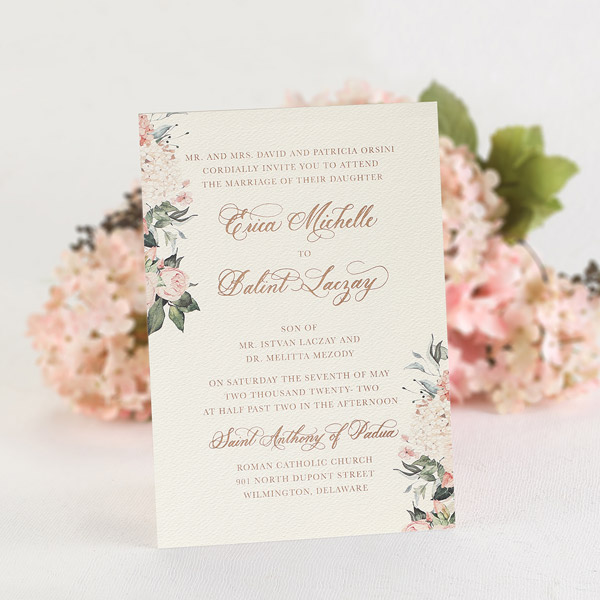 An elegant wedding invitation with floral accents is displayed in front of a hydrangea bouquet.