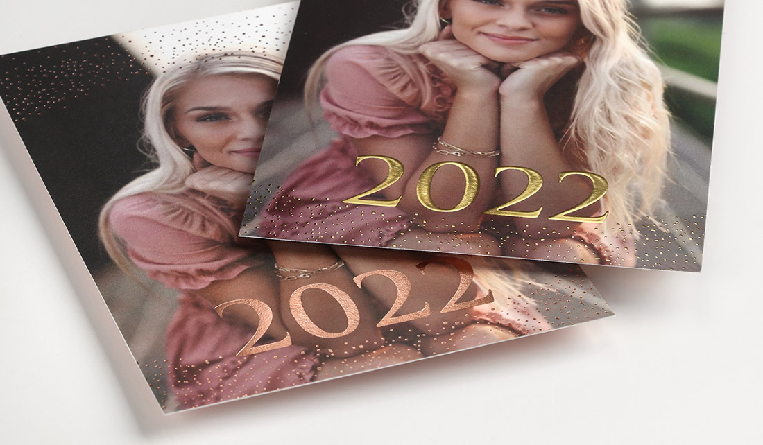 A photo graduation announcement with traditional foil stamping is shown next to one with enhanced foil.