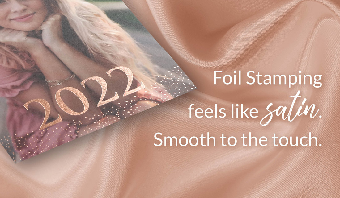 An image of a foil-stamped card is laid on top of pink satin to show that it feels like satin. 