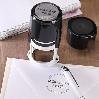 Custom address stamp with round return address in black on an envelope.